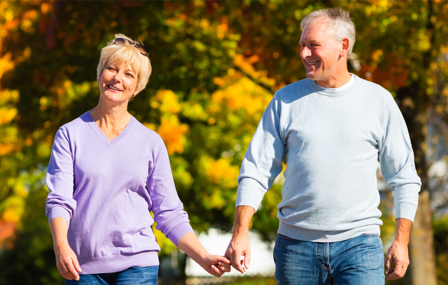 senior couple, Man and woman, having a walk in autumn or fall outdoors, the trees show colorful foliage